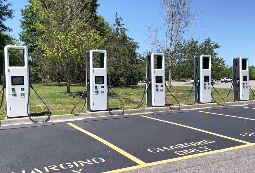 electric charging station with many electric chargers and a parking lot on a sunny day.