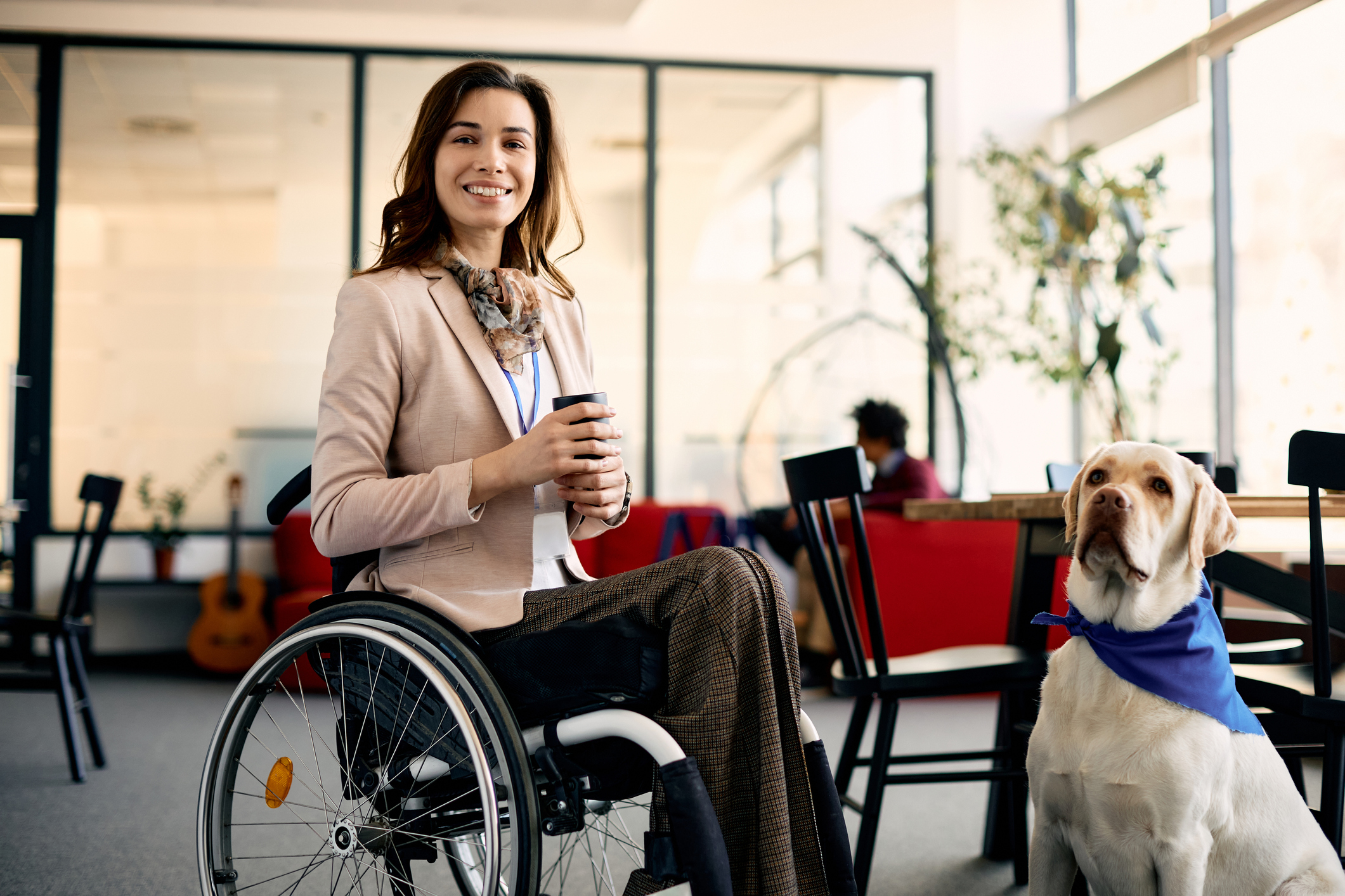 Happy businesswoman with disability and her assistance dog enjoying during her coffee break at work.