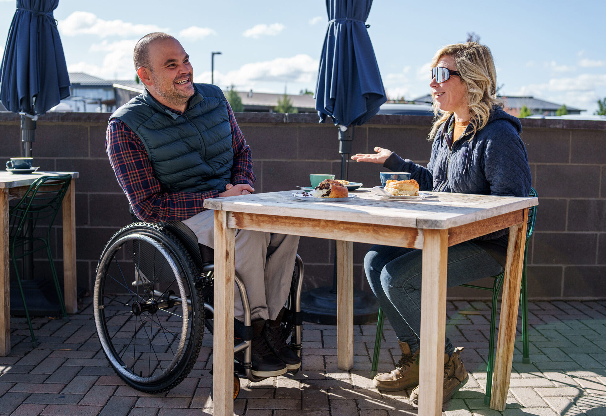 woman sitting at a table on a roof top with man in wheelchair
